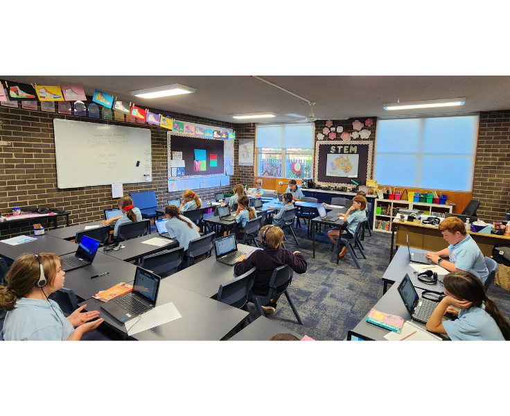 Classroom with children working on laptops some with headphones on