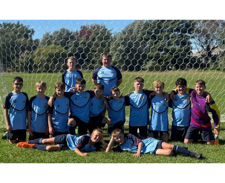 Boys soccer team posing as a group in front of soccer nets